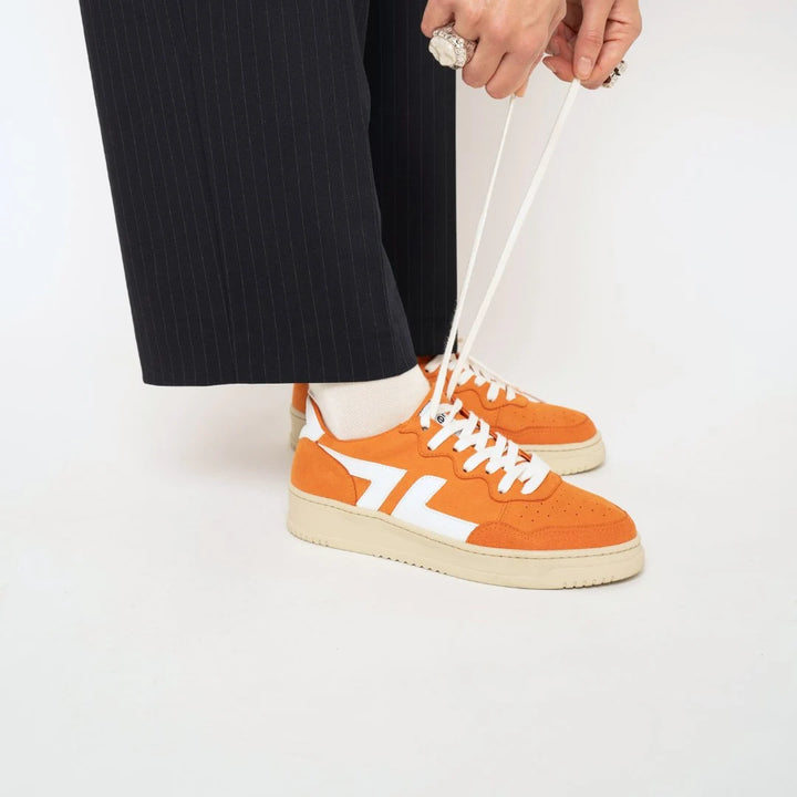 Baskets oranges Beta B3 portées, apportant dynamisme et couleur aux looks quotidiens.