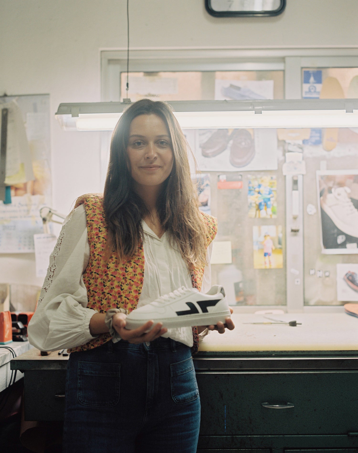 Laure, fondatrice de Zèta, en visite dans les ateliers de fabrication des baskets au Portugal. Elle tient le modèle Alpha dans les mains.